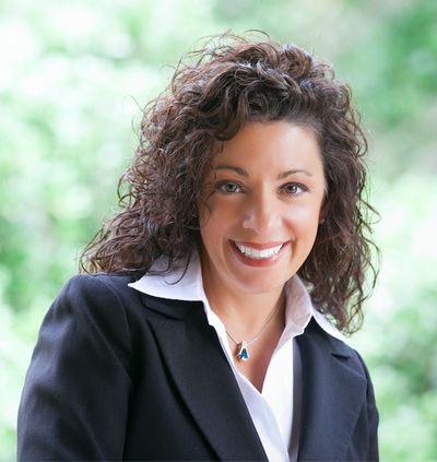 Lisa DeFalco in a dark blazer, pictured against a green outdoor background